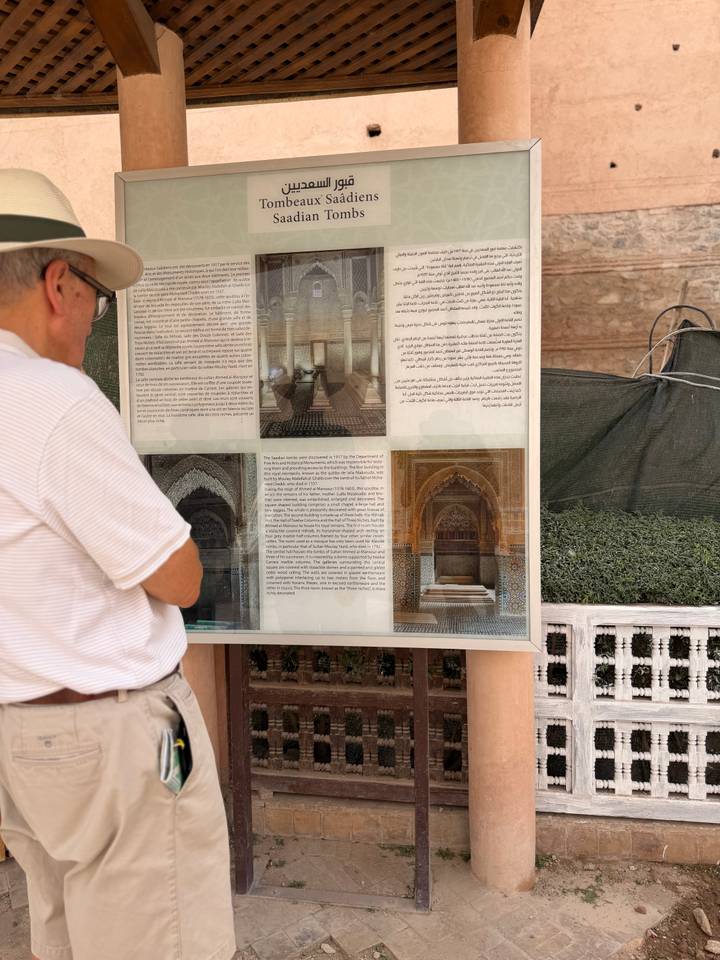 Visitor reading an informational board with Arabic and English text at a historic site.