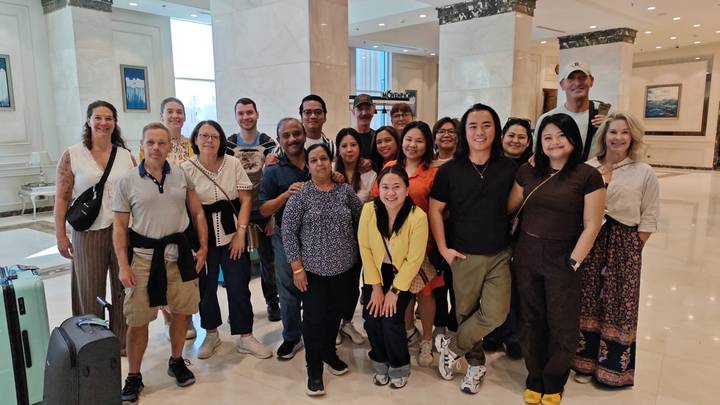 Large tour group posing together in a hotel lobby.
