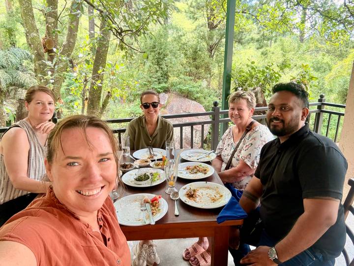 Friends enjoying a meal at an outdoor restaurant table with empty plates.