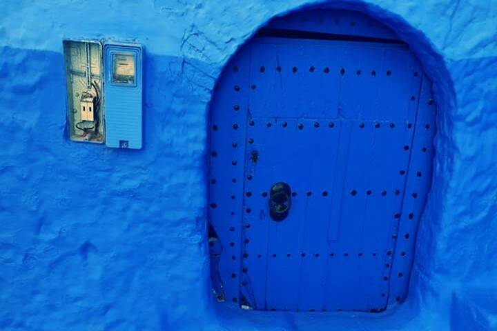 Vivid blue plastered doorway with metal studs in the blue city streets of Chefchaouen.
