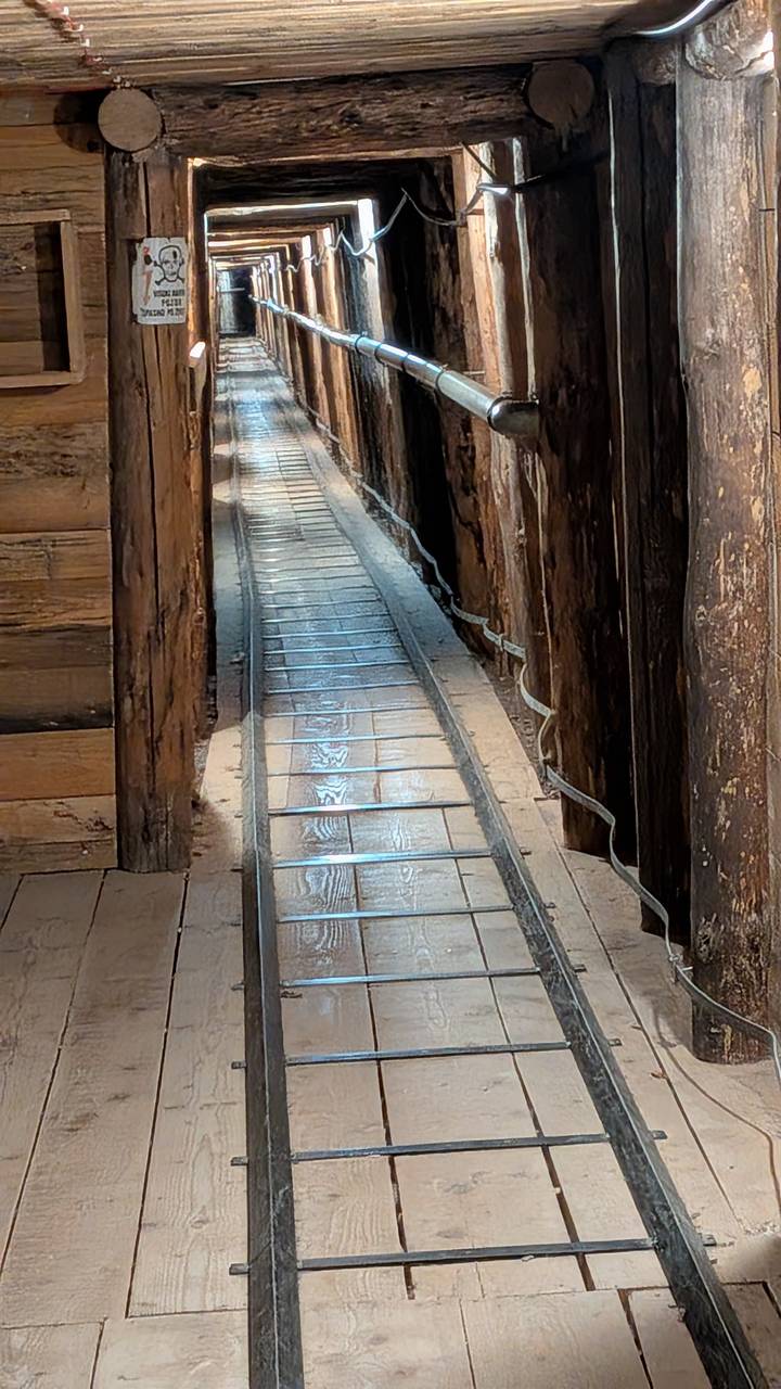 Interior view of narrow wooden passageway with metal rail tracks inside the Sarajevo War Tunnel.