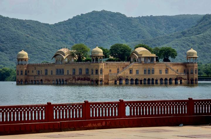 Jal Mahal palace sitting gracefully in the middle of a tranquil lake with green hills behind