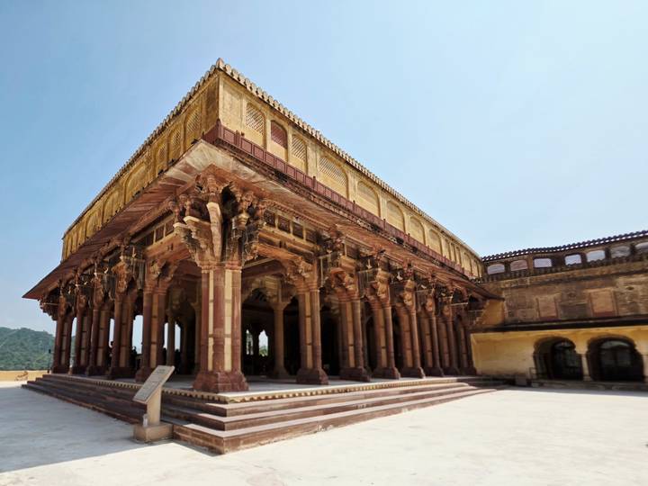 Intricately carved pillared hall of Amber Fort glowing in warm sunlight