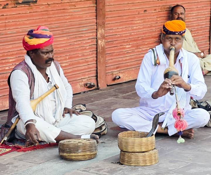 Snake charmer duo in turbans performing with a cobra basket on a street