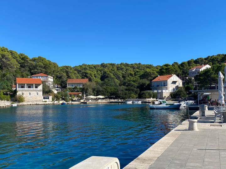 Small coastal village with red-roofed houses lining a tranquil blue harbor.