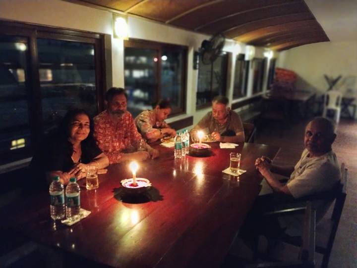 Small group enjoying a candlelit dinner around a wooden table in a dimly lit restaurant.