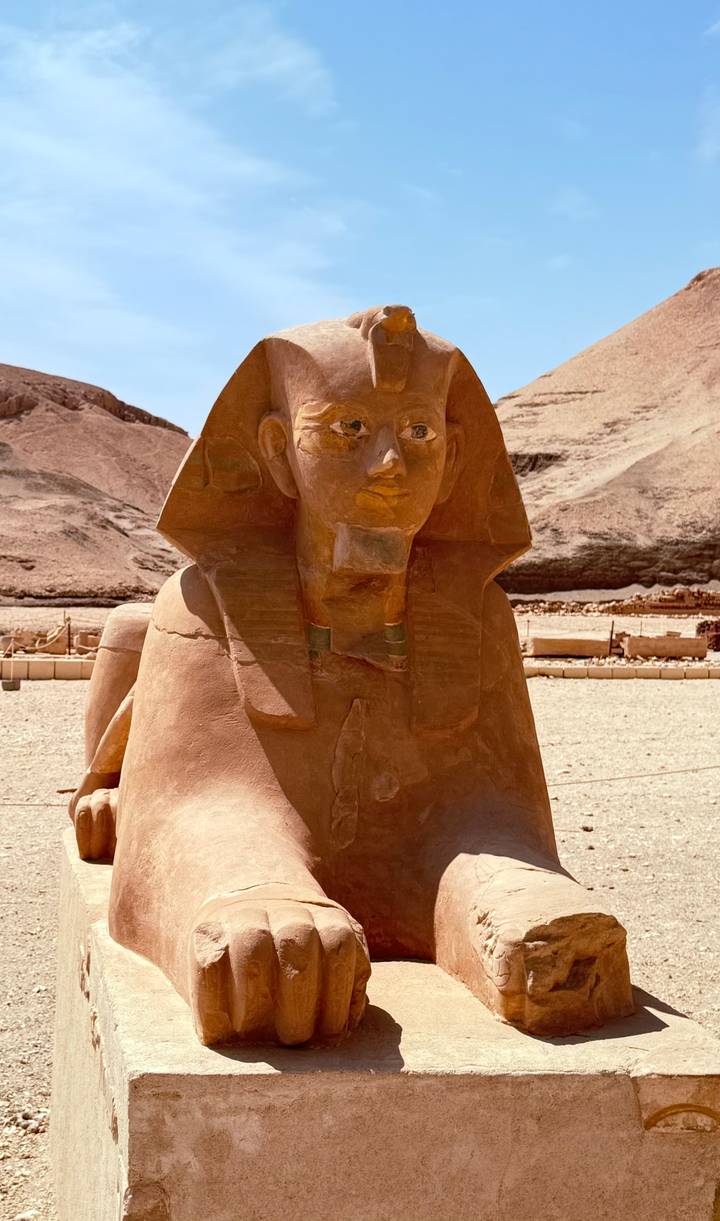Sphinx-style statue carved from stone displayed in an open archaeological site.