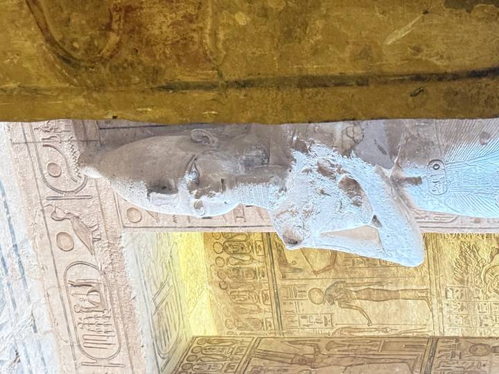 Relief-covered statue inside a richly decorated ancient Egyptian temple chamber.