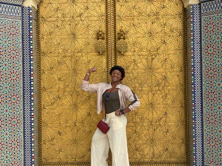 Woman posing in front of the ornate golden doors of the Royal Palace in Fes.