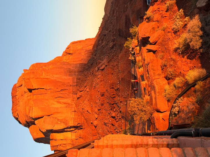A solitary red sandstone butte glows in warm sunset light against a clear sky.