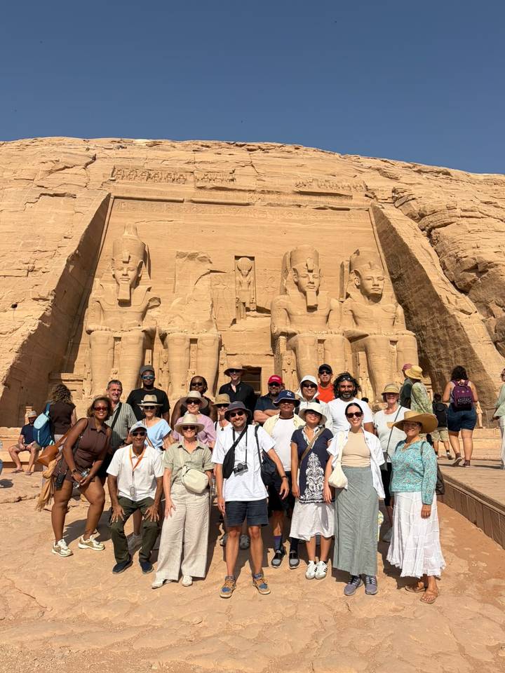 Tour group standing before the colossal seated statues of Abu Simbel temple
