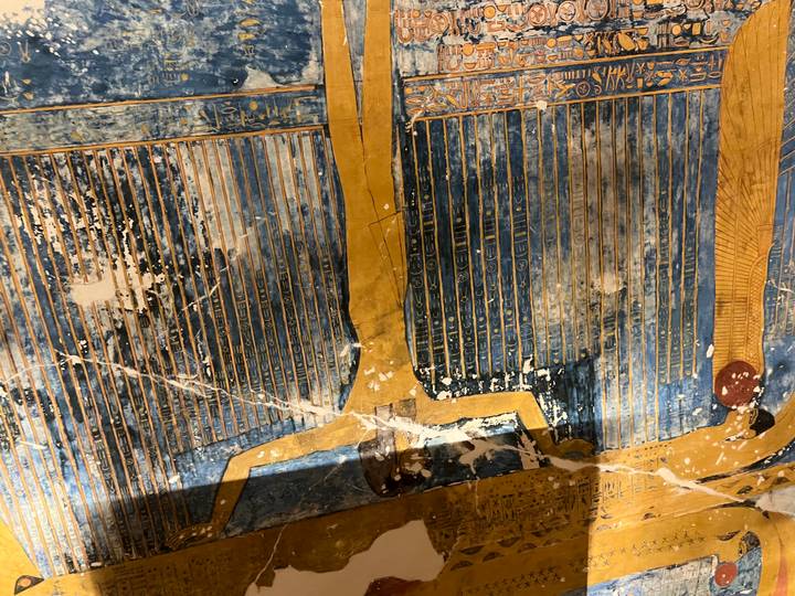 Aged painted ceiling inside Egyptian tomb depicting figure and hieroglyphs