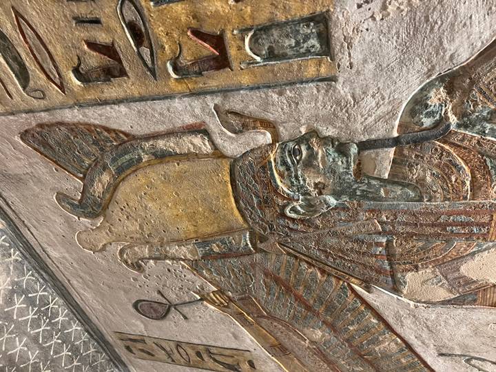 Close detail of carved Egyptian deity with colourful pigment remnants