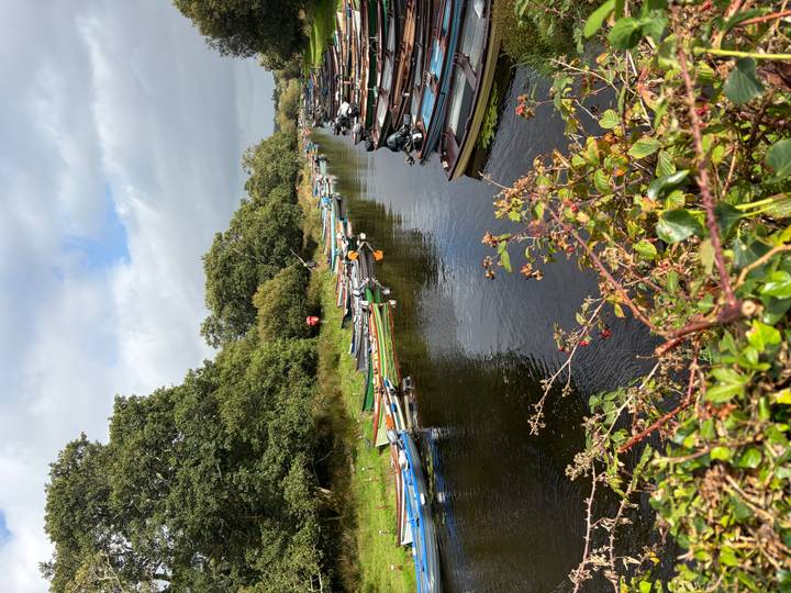 Narrow river lined with dozens of small colorful fishing boats and leafy banks