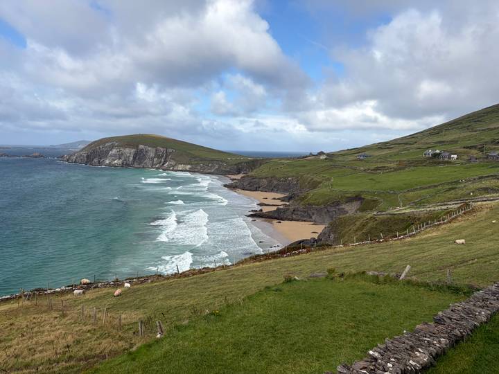 Dramatic Atlantic coastline with green hills and crashing waves on a sandy beach