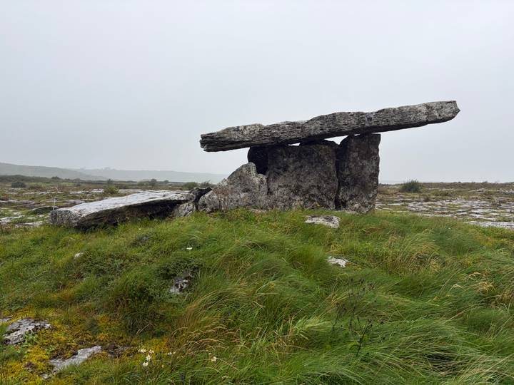 Ancient stone dolmen standing on a grassy limestone plain under gray sky