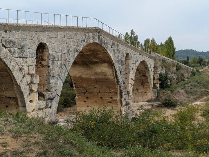 Old stone bridge with multiple arches spanning a dry creek bed in the countryside