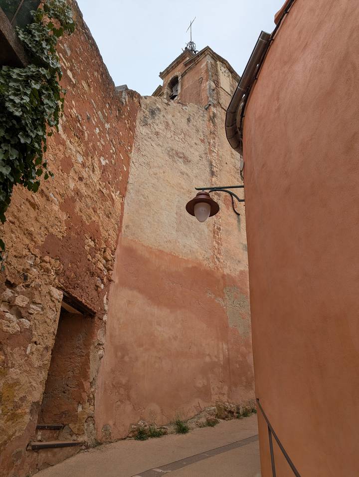 Narrow village alley with textured ochre walls and a single vintage lamp