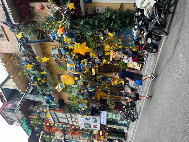 Colorful storefront covered in star decorations draws tourists and locals on a Vietnamese street.