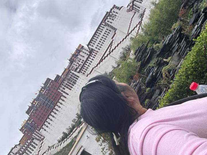 Traveler gazes at the majestic Potala Palace rising above Lhasa’s skyline on a cloudy day.