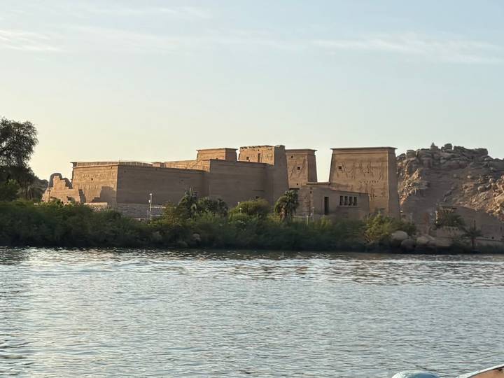Ancient temple complex sits on an island in the Nile with warm evening light.