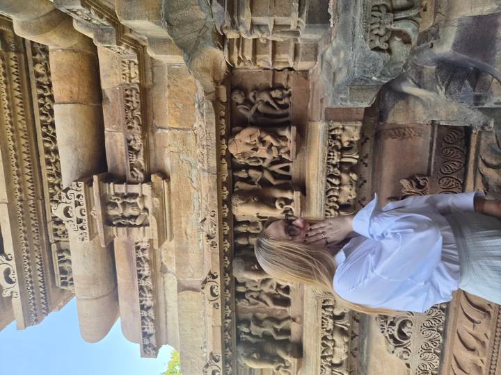 Woman observing detailed stone carvings on an ancient temple wall