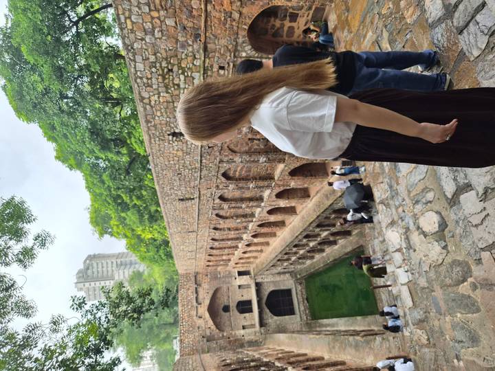 Traveler overlooking a multi-level medieval stepwell surrounded by stone arches