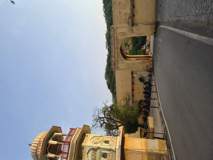 Quiet roadway leading through a yellow arched gate near forested hills