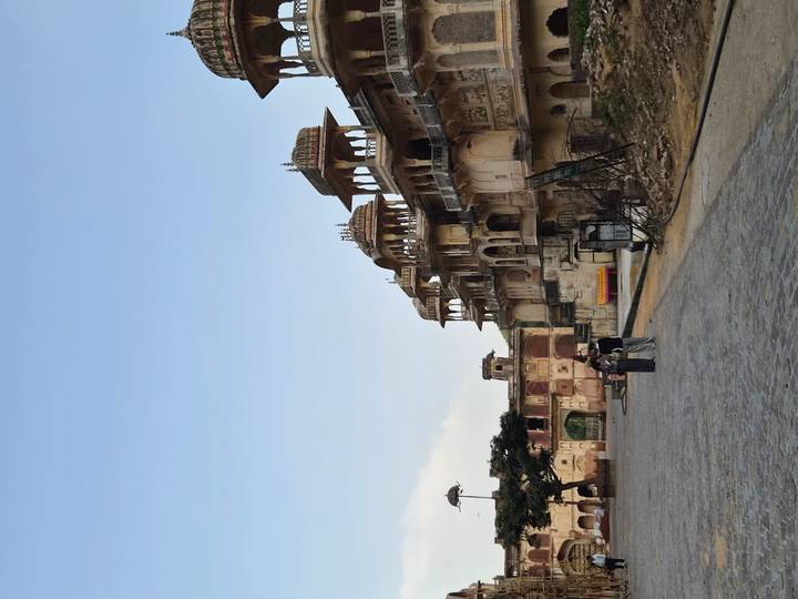 Historic, weathered palace complex with ornate balconies along a cobblestone square
