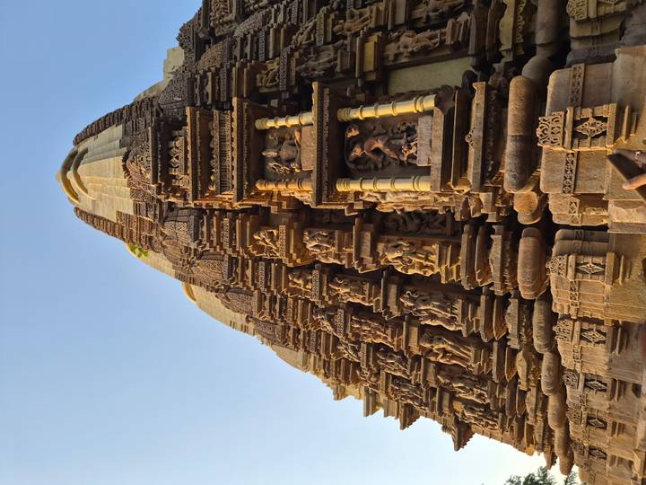 Detailed carvings on a vertical stone temple tower lit by late afternoon sun