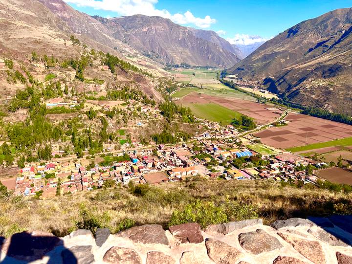 Panoramic view over the Sacred Valley with patchwork farms and rugged mountains.