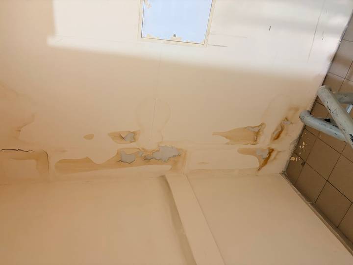 Peeling paint and cracks on an interior stairwell wall showing water damage
