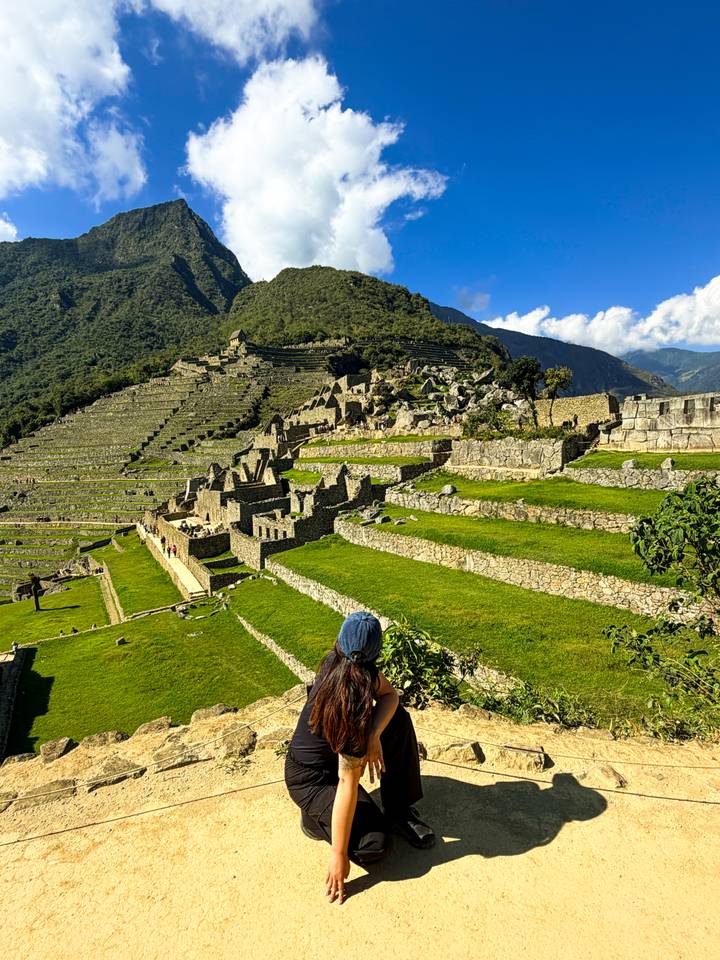 Lush green terraces and ruined stone walls of Machu Picchu viewed from above.