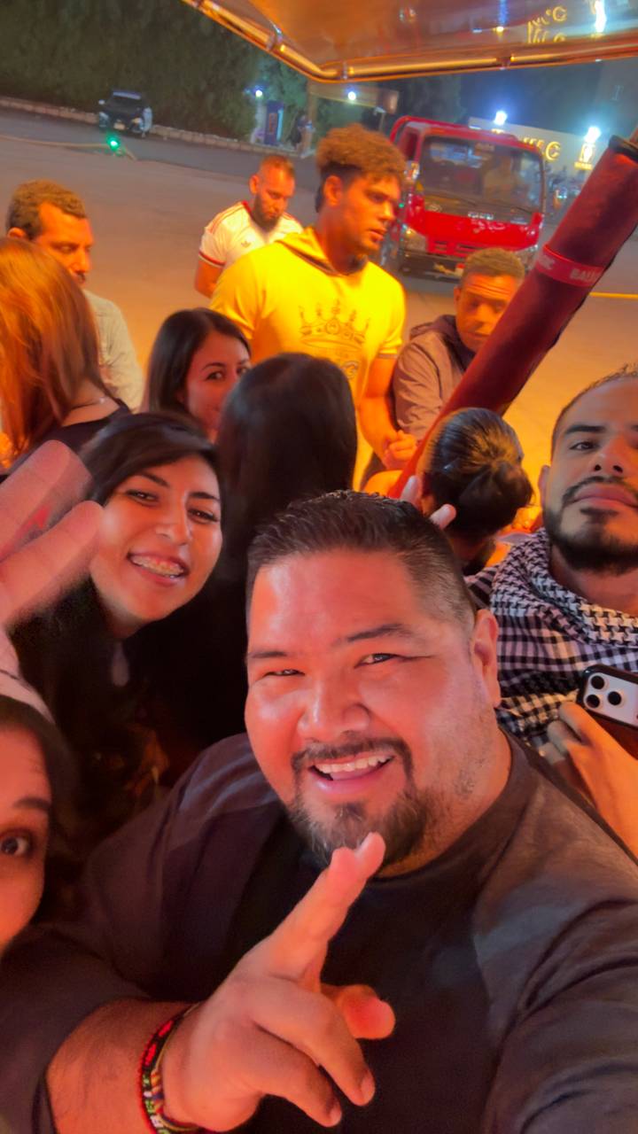 Close-up selfie of smiling friends in a lively crowd.