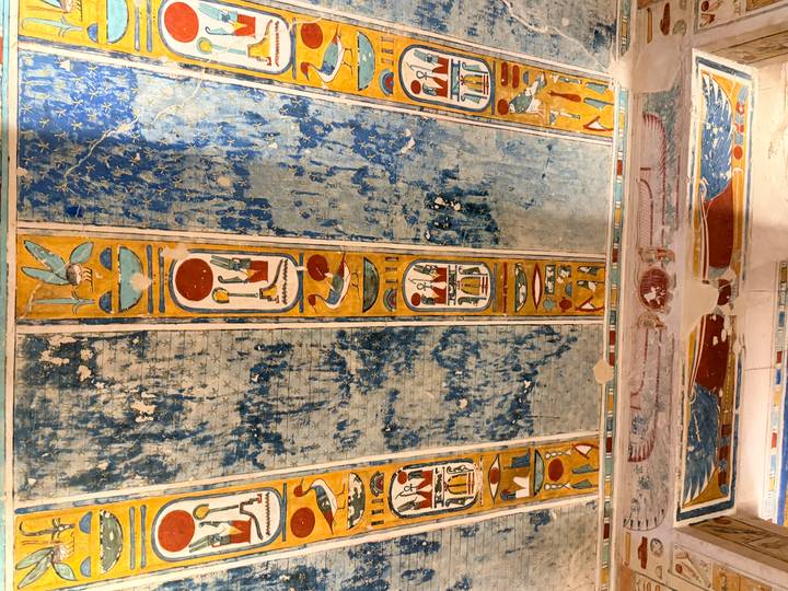 Colorful ancient Egyptian ceiling panels decorated with hieroglyphs and deities.