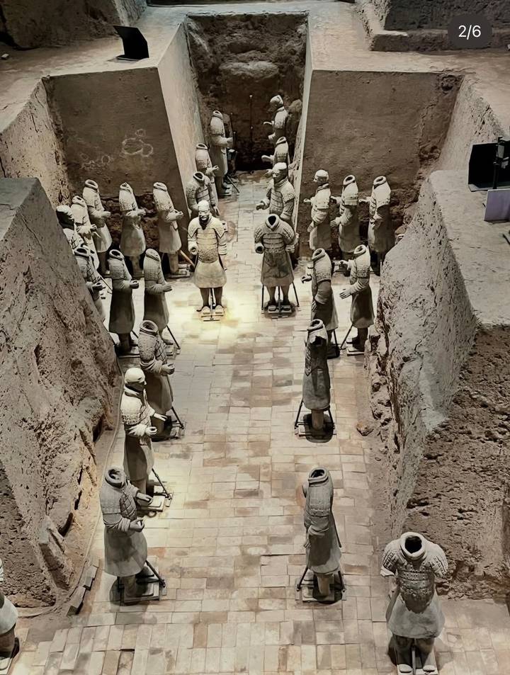 Excavation pit of the Terracotta Army with rows of headless clay soldiers standing along a tiled floor.