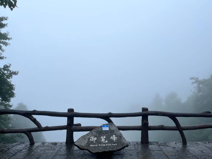 Foggy viewpoint with a wooden fence barely visible against a blank grey sky.