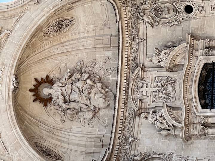 Ornate baroque stone relief depicting religious figures above a cathedral entrance.