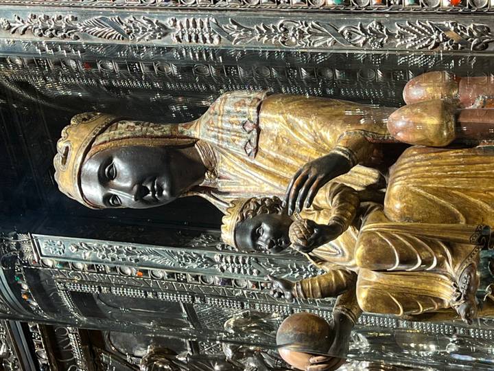 Iconic Black Madonna sculpture with child displayed behind protective glass.