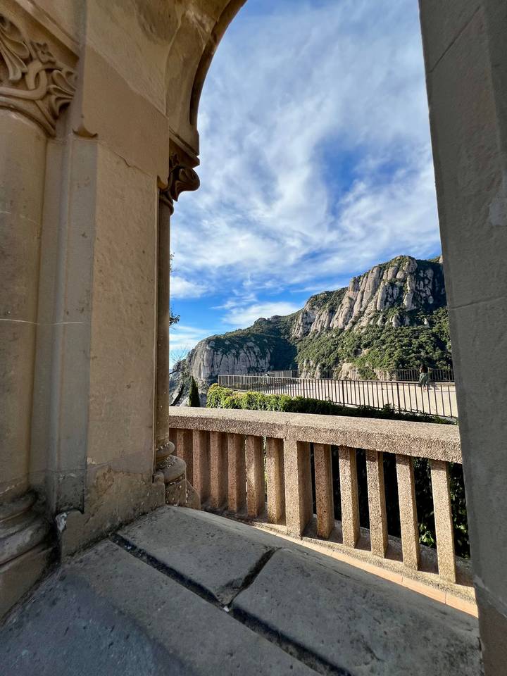 Rocky massif of Montserrat framed by stone terrace and blue sky.