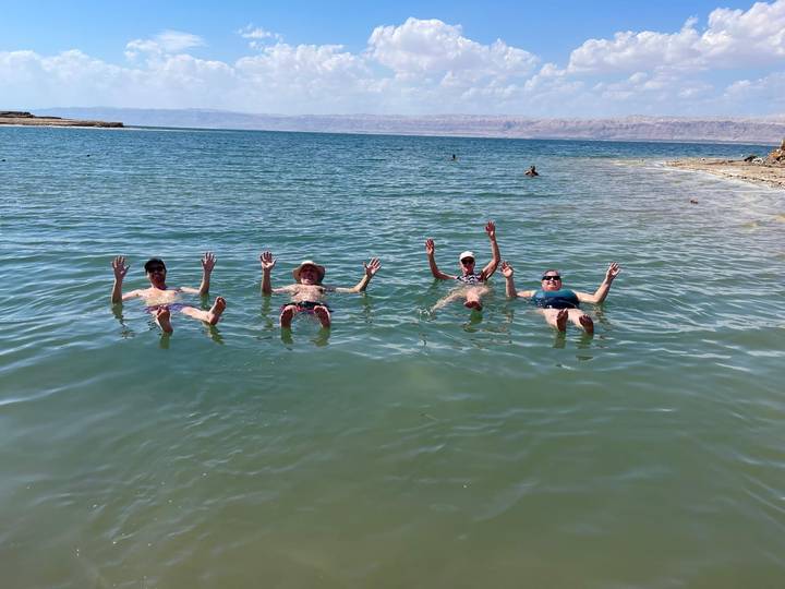 Four travellers floating effortlessly on their backs in the salty waters of the Dead Sea.