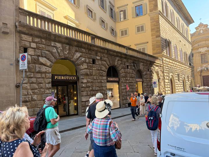 Busy shopping street in Florence with tourists walking past the Pierotucci leather store.