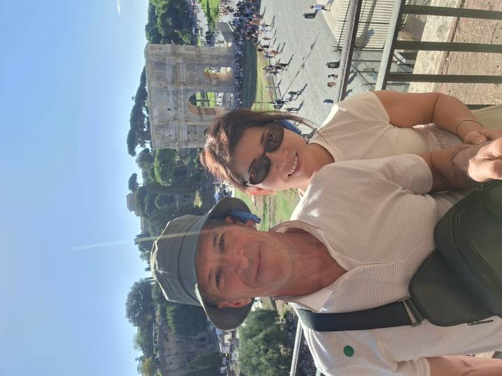 Couple selfie overlooking Rome’s Arch of Constantine and ancient ruins under a clear blue sky.