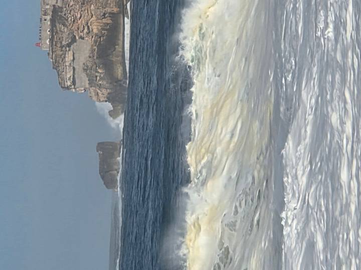 Powerful Atlantic waves crashing below the cliffs and lighthouse near Nazaré.