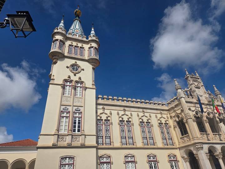 Neo-Manueline town hall building with ornate turret and Portuguese flag under blue sky in Sintra.