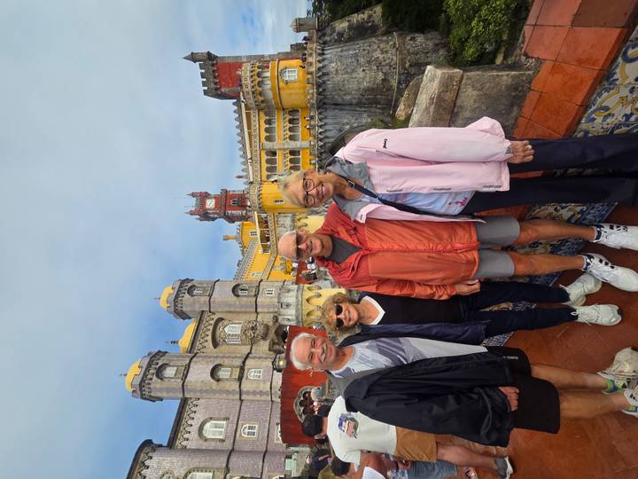 Smiling tour group posing in front of the colorful Pena Palace terraces.
