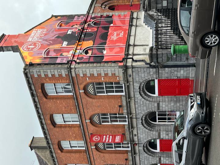 Historic Smithwick’s brewery building with colorful mural and red doors on a city street.