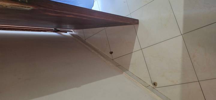 Partially open wooden door and tiled floor corner in a dim hallway.