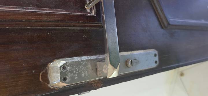 Close-up of a worn metallic door handle on a dark wooden door.