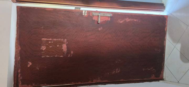 Full wooden door with peeling and scratched paint revealing underlying layers.